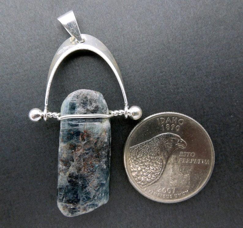 blue kyanite pendant next to a quarter