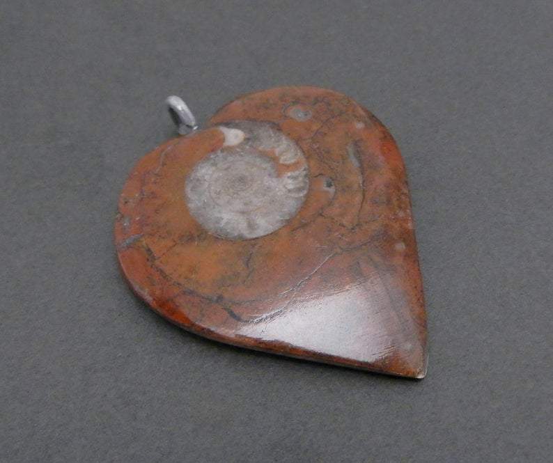 close up of heart shaped ammonite pendant with silver plated bail showing design