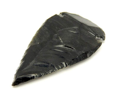 Black obsidian arrowhead close up on a a white background.