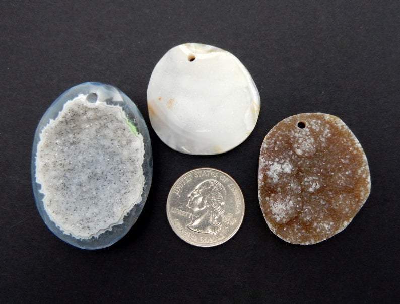 3 Different Druzy Agate in Top Center Drilled Next to a Quarter on Black Background.