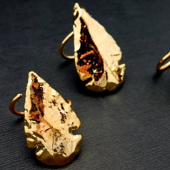 2 Gold Dipped Arrowhead Ring with Electroplated 24k Gold Edges on an Adjustable Bands on a table