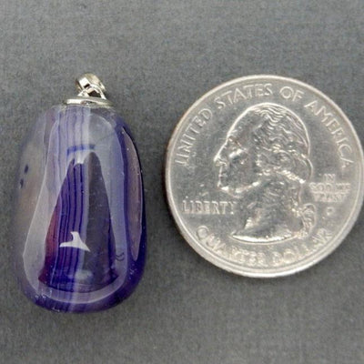 pendant displayed next to quarter for size reference