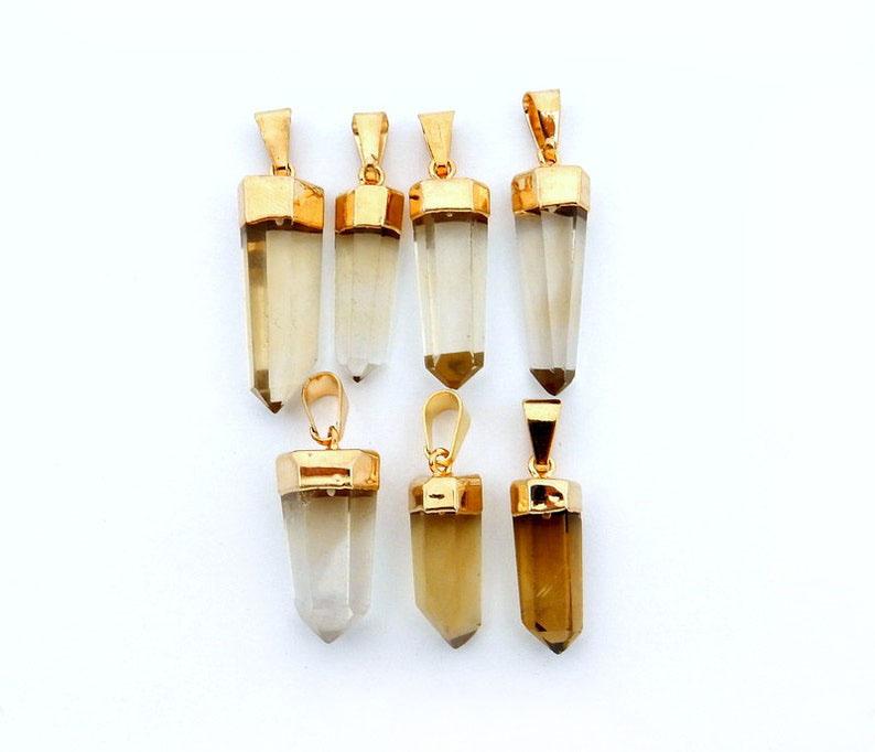 many smokey quartz point pendants in a row on white background for possible variations