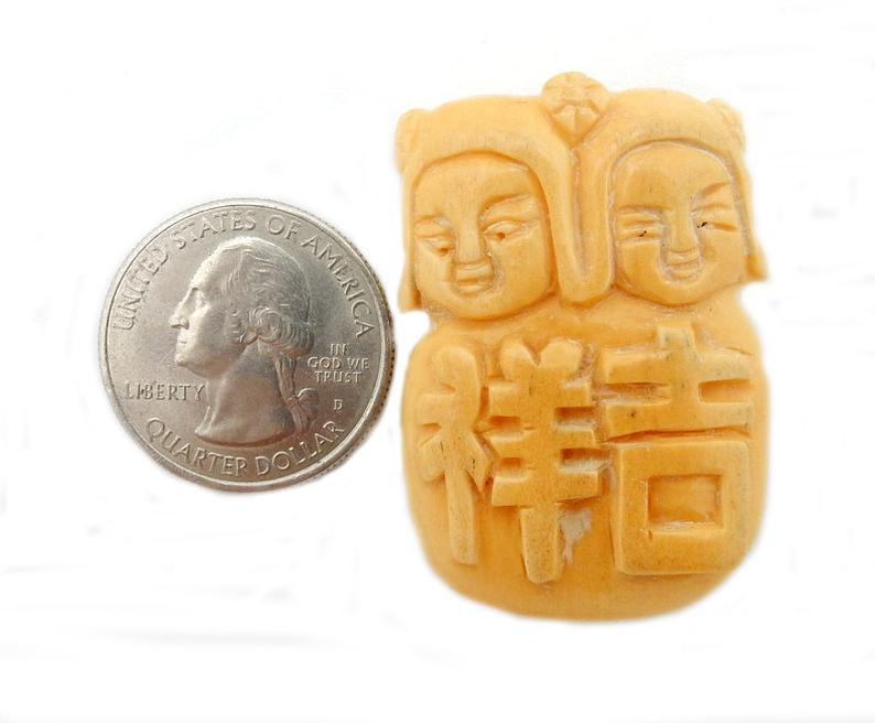 Chinese Carved Bone Top to Bottom Drilled Bead next to a quarter for size refernce