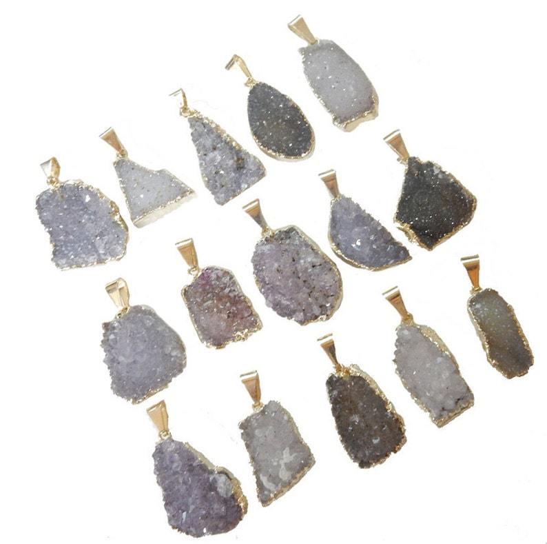 15 Freeform Amethyst Druzy Pendants with Gold electrop;lated edge displayed on a table showing range of size, shape, colors.