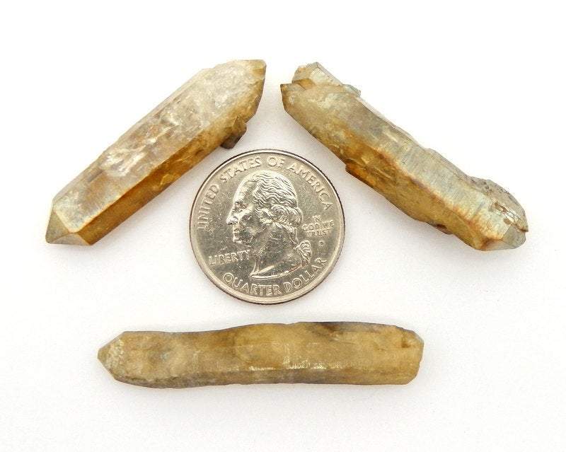 3 Products Gold Toned Titanium Treated Crystal Quartz Points surrounding a quarter for size reference