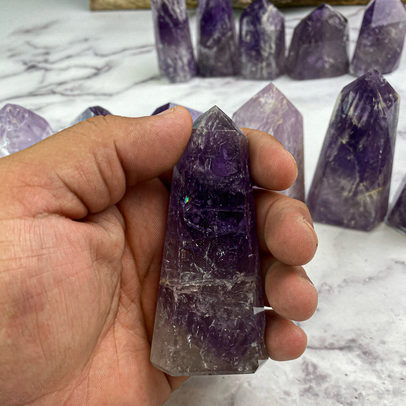 polished amethyst points in hand for size reference