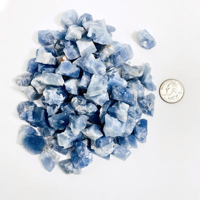 top view of pile of blue calcite next to a quarter for size reference