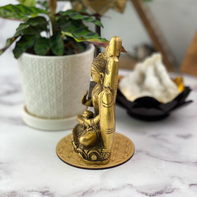 Side view of A brass hand with a buddha sitting inside of it.