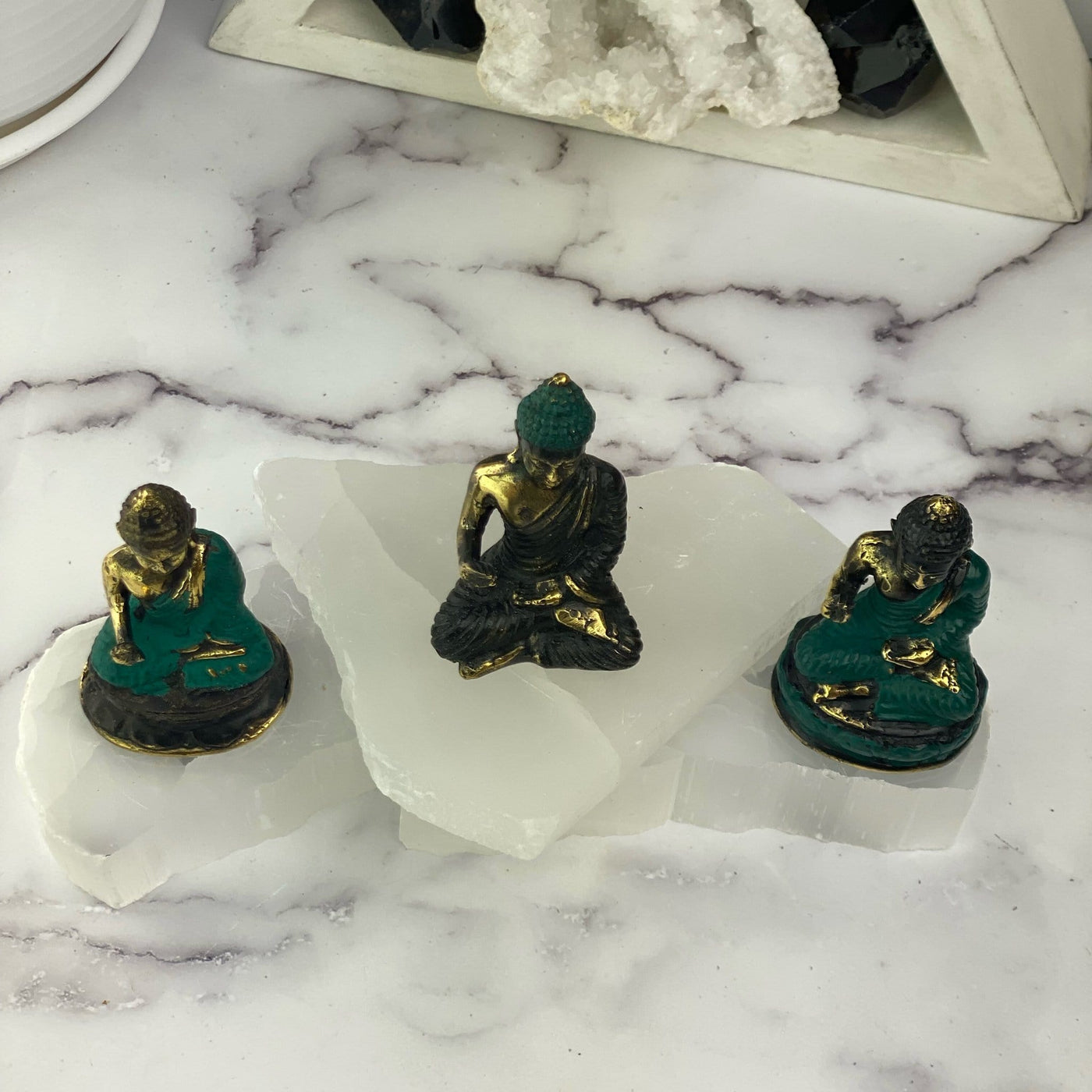 top view of 3 Buddha mini statues with decorations in the background