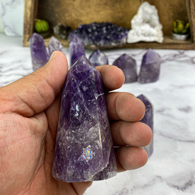 polished amethyst points in hand for size reference