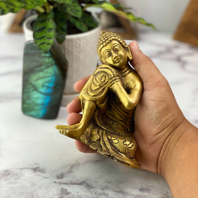 hand holding up Brass Resting Buddha Gold Head on Knee Statue 