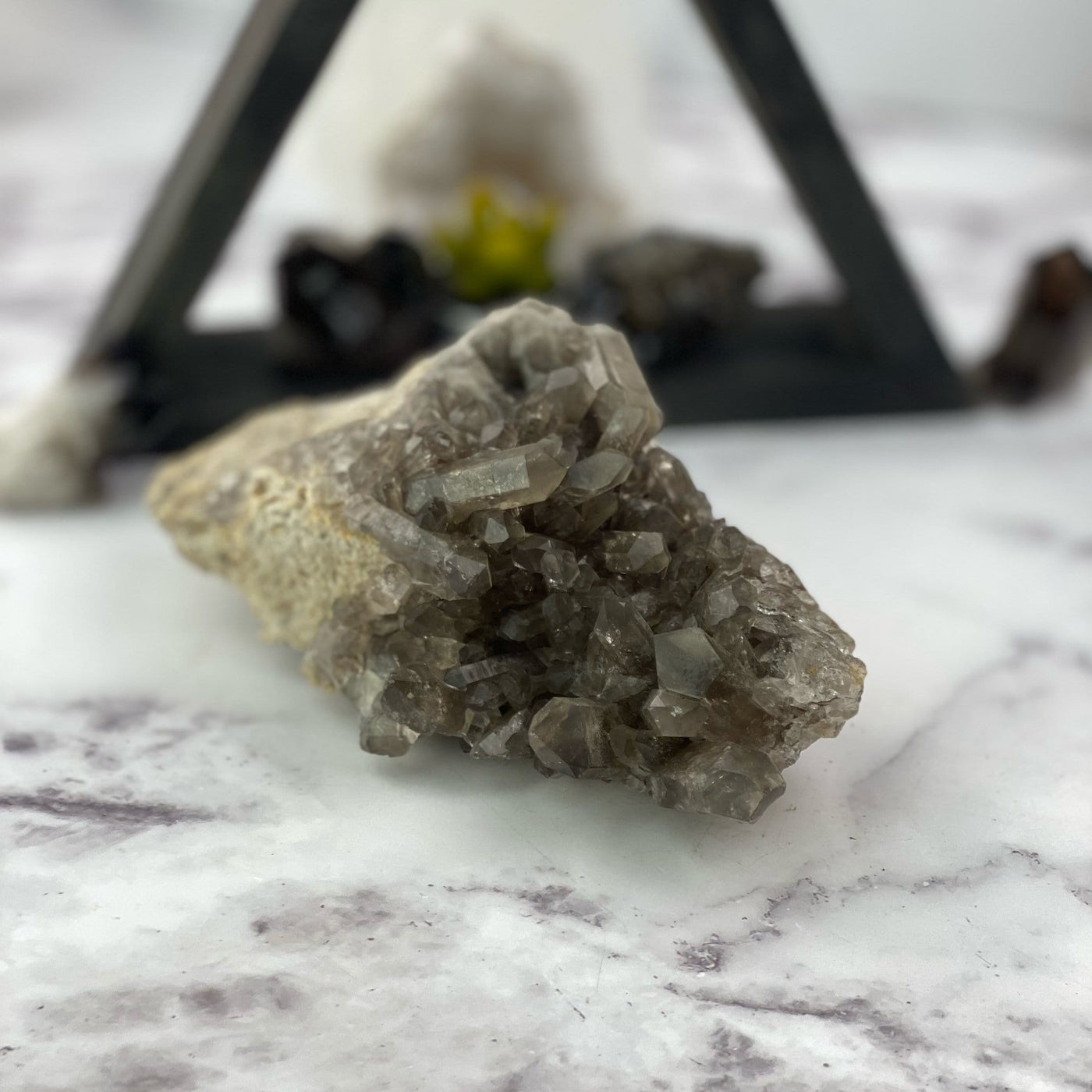 close up of natural smokey quartz cluster in front of backdrop for details