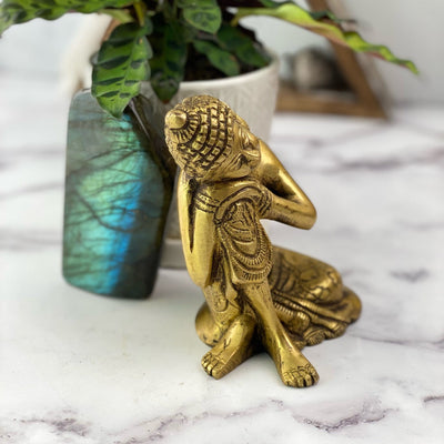 angled shot of Brass Resting Buddha Gold Head on Knee Statue with decorations in the background