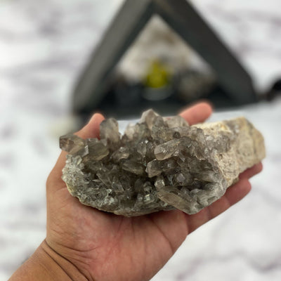 natural smokey quartz cluster in hand for size reference