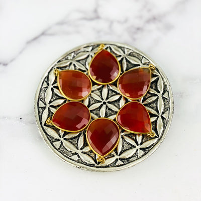 birds eye view of 6 carnelian teardrops on a brass plate with a white marble background