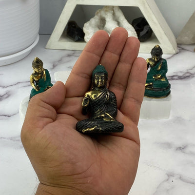 hand holding up Buddha mini statue with others in the background