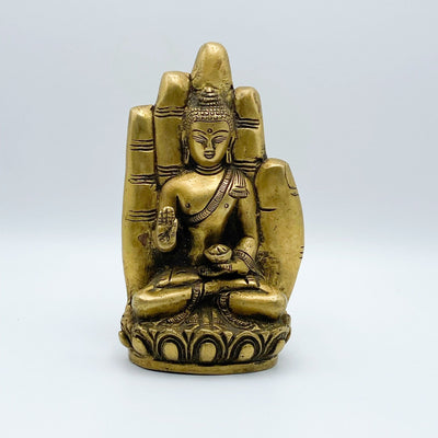 A brass hand with a buddha sitting inside of it.