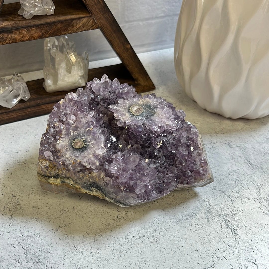 Amethyst stalactite cluster.  It has two stalactite eyes on the top. On a cement background.