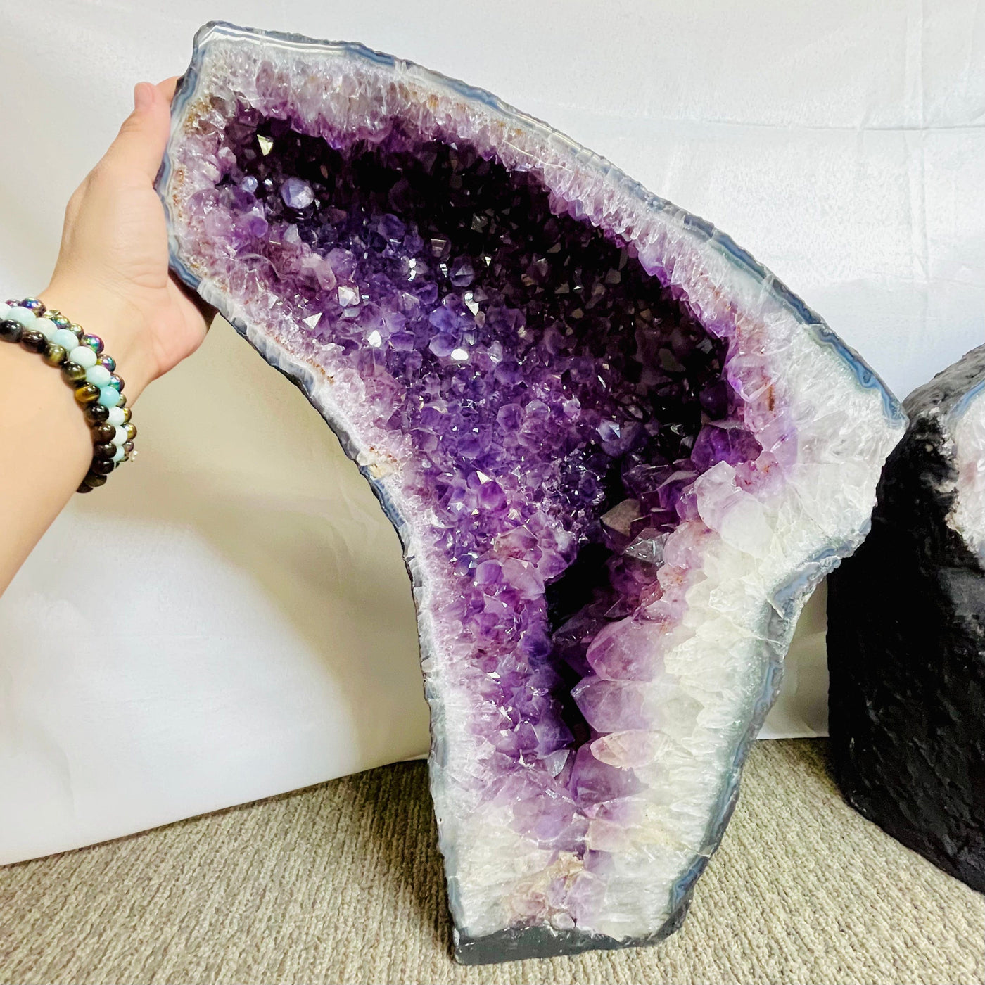 Up close view of left Large Amethyst Sliced Geode Wing with woman's hand placed on the upper side of it.