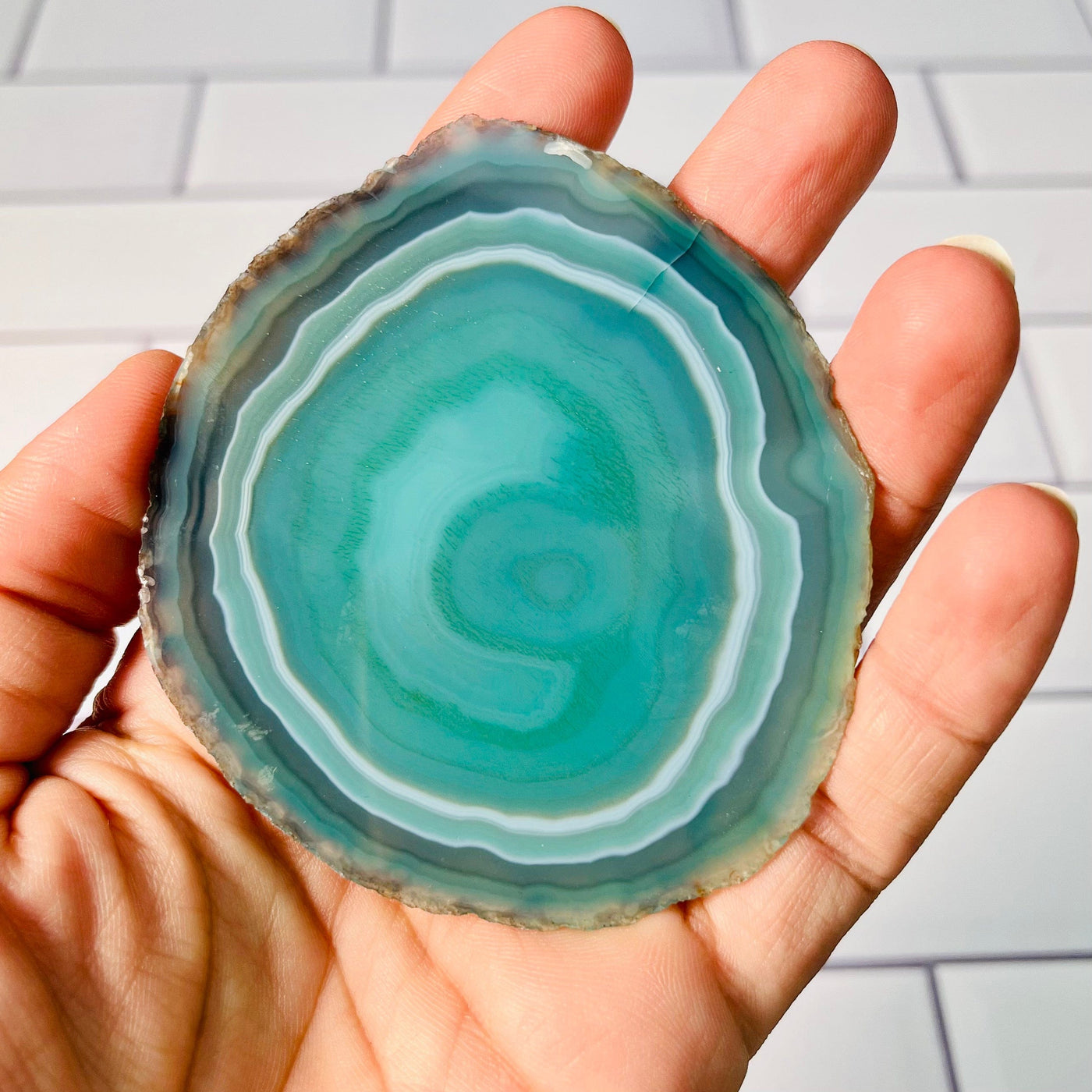 Back view of smallest Agate Slice, green color and held in a woman's hand.