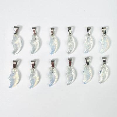Twelve Opalite Crescent Moon Gemstones Pendants lined up in two rows on a white surface.