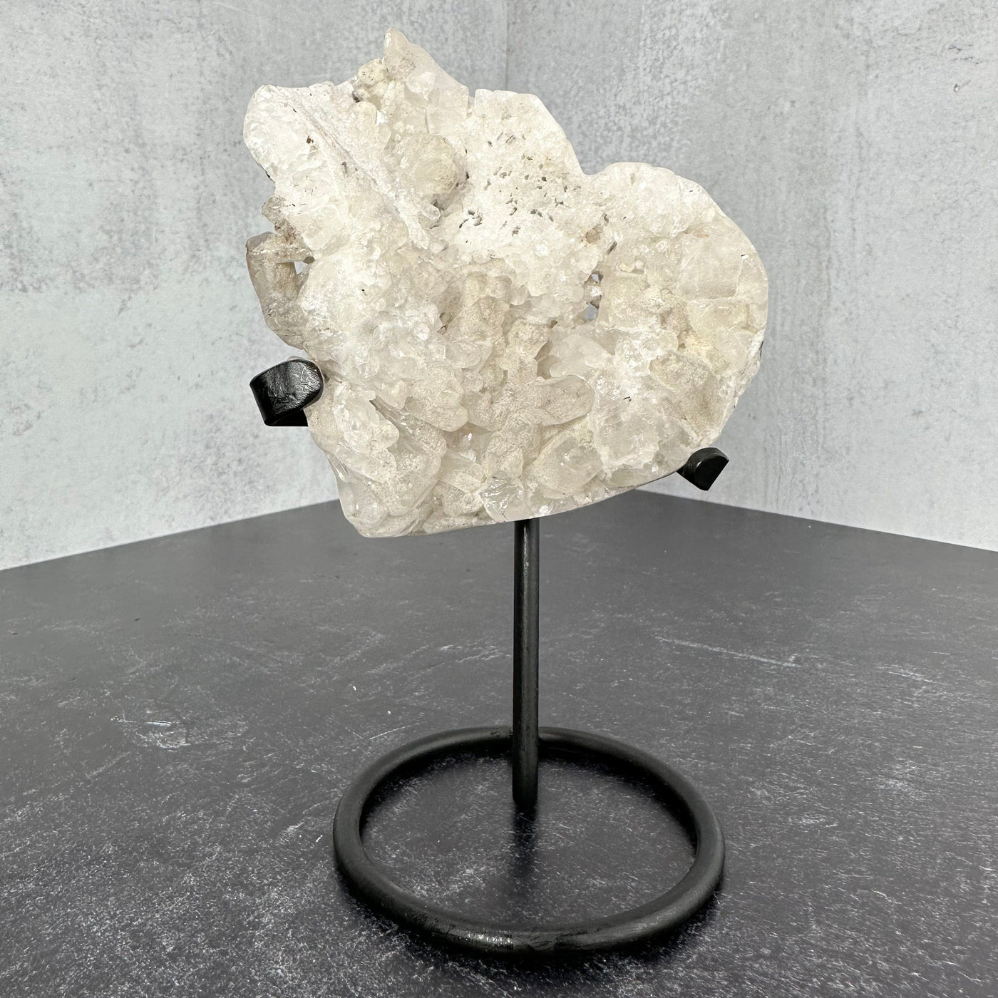 Frontal view of Crystal Quartz Abstract Heart on Metal Stand on a black surface.