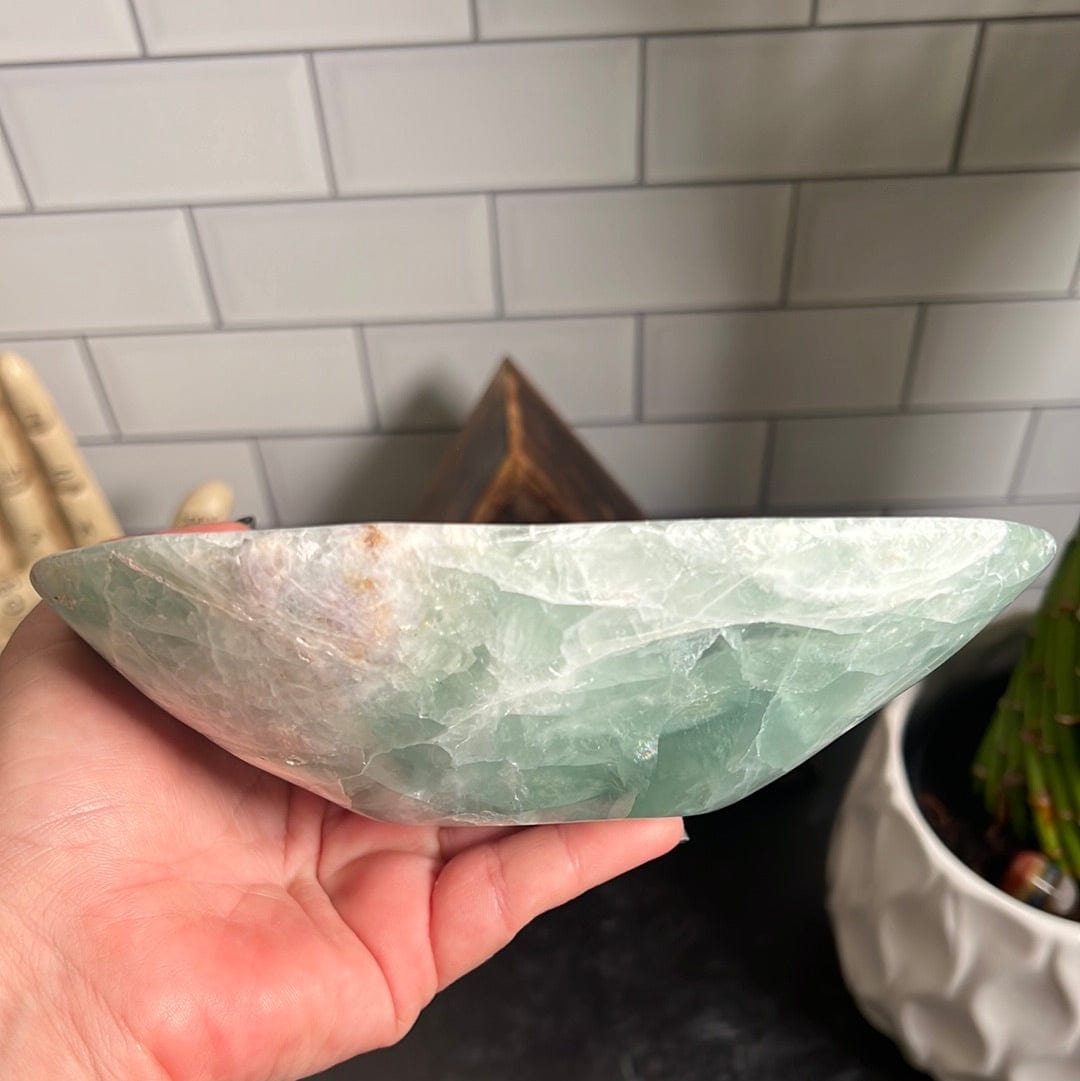 Green fluorite bowl held up by a woman's hand.