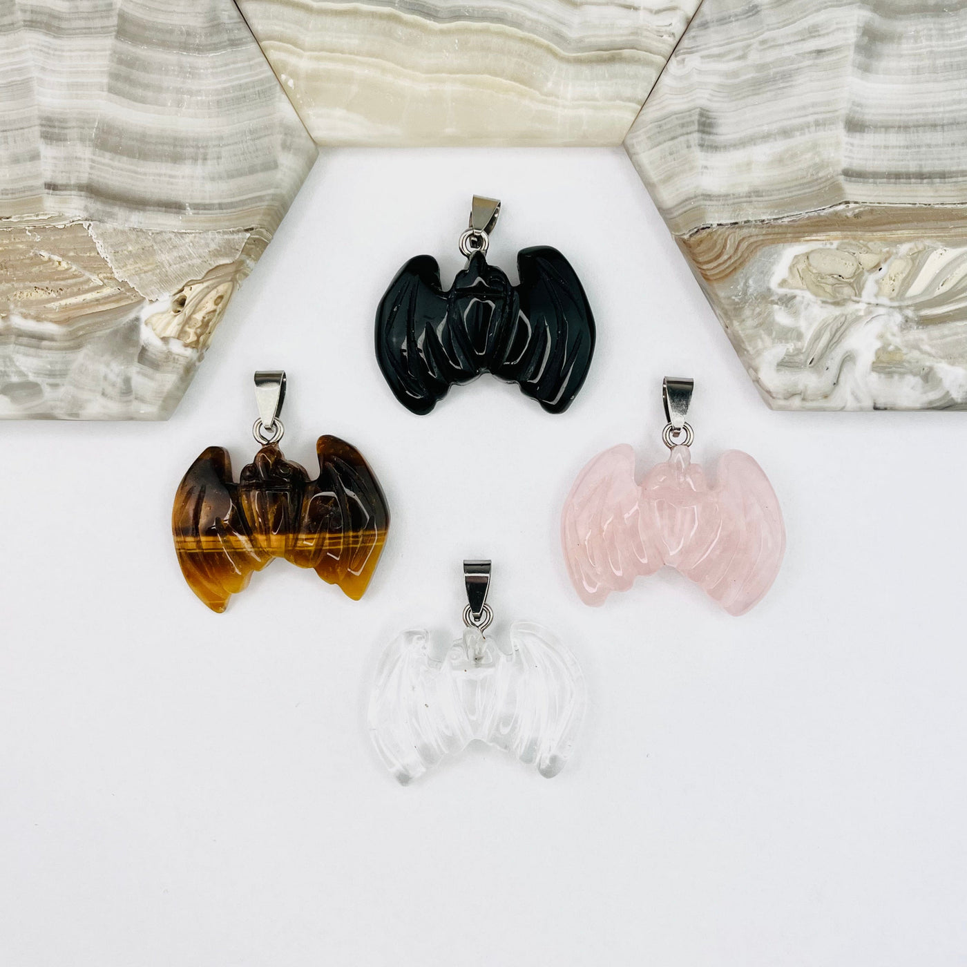 One of each of the Four types of Bat Gemstone Pendants  on a white surface.