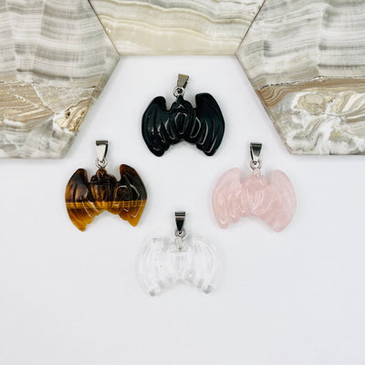 One of each of the Four types of Bat Gemstone Pendants  on a white surface.
