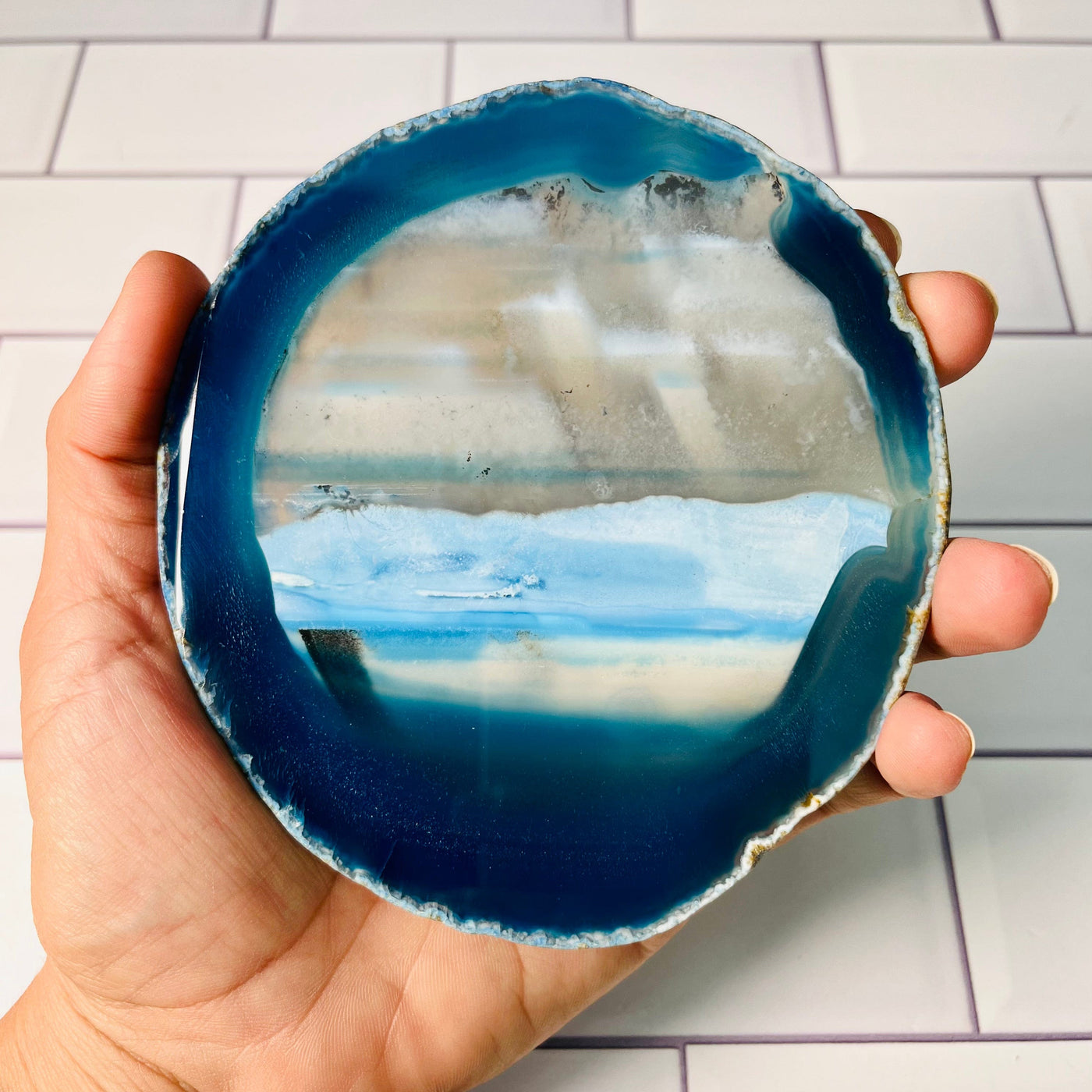 Back view of largest Agate Slice, blue grey and greenish hues. Held in a woman's hand.