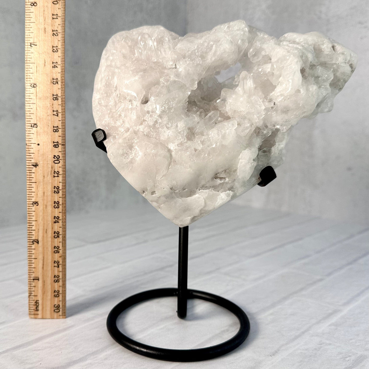 Frontal view of Crystal Quartz Cluster Heart on Metal Stand next to a ruler for size reference.