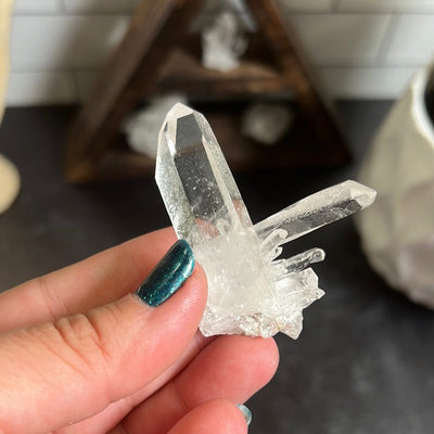 Crystal Cluster that has two larger points.  One is pointing up and the other to the side with smaller points below it.  Held in a woman's hand.