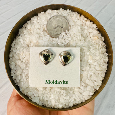 Moldavite earrings displayed on their display card next to a quarter for size reference.