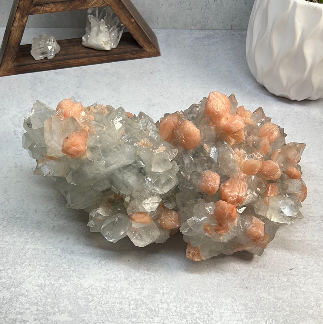 Large zeolite cluster with apophyllite and peach stillbite crystals on a gray background.