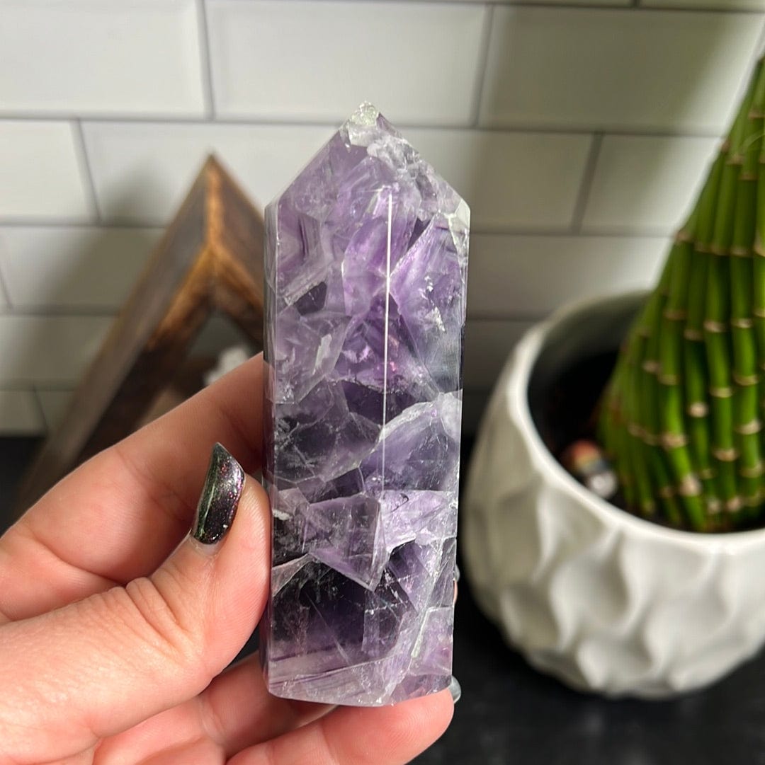 Purple polished fluorite point held in a woman's hand.