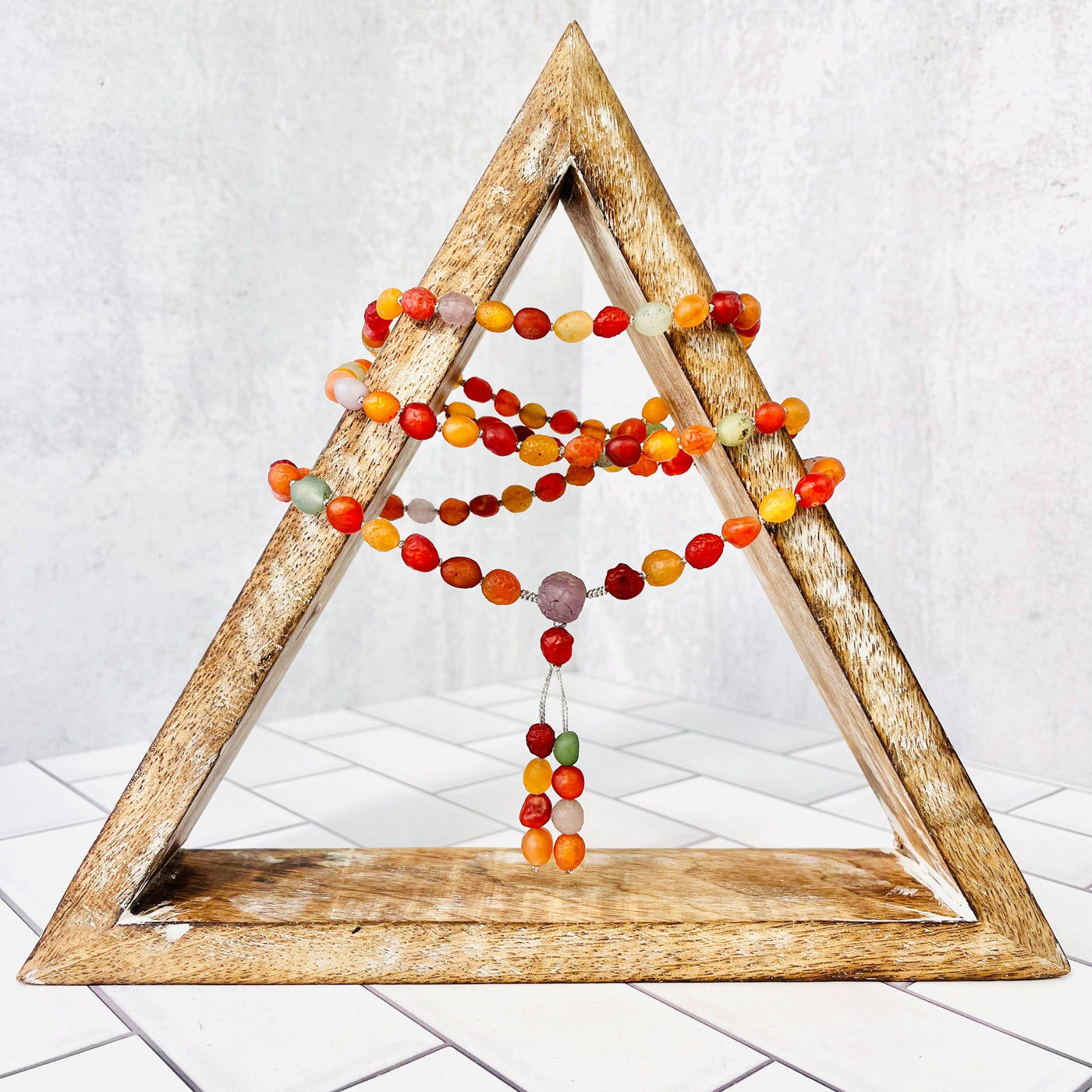 Gobi Desert Agate Mala Bead Necklace displayed on a wooden triangle, wrapped around and hanging down center. 