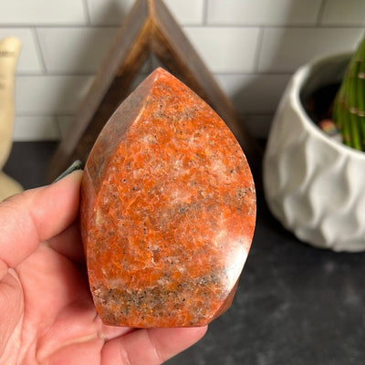 Orange calcite flame held in a woman's hand.