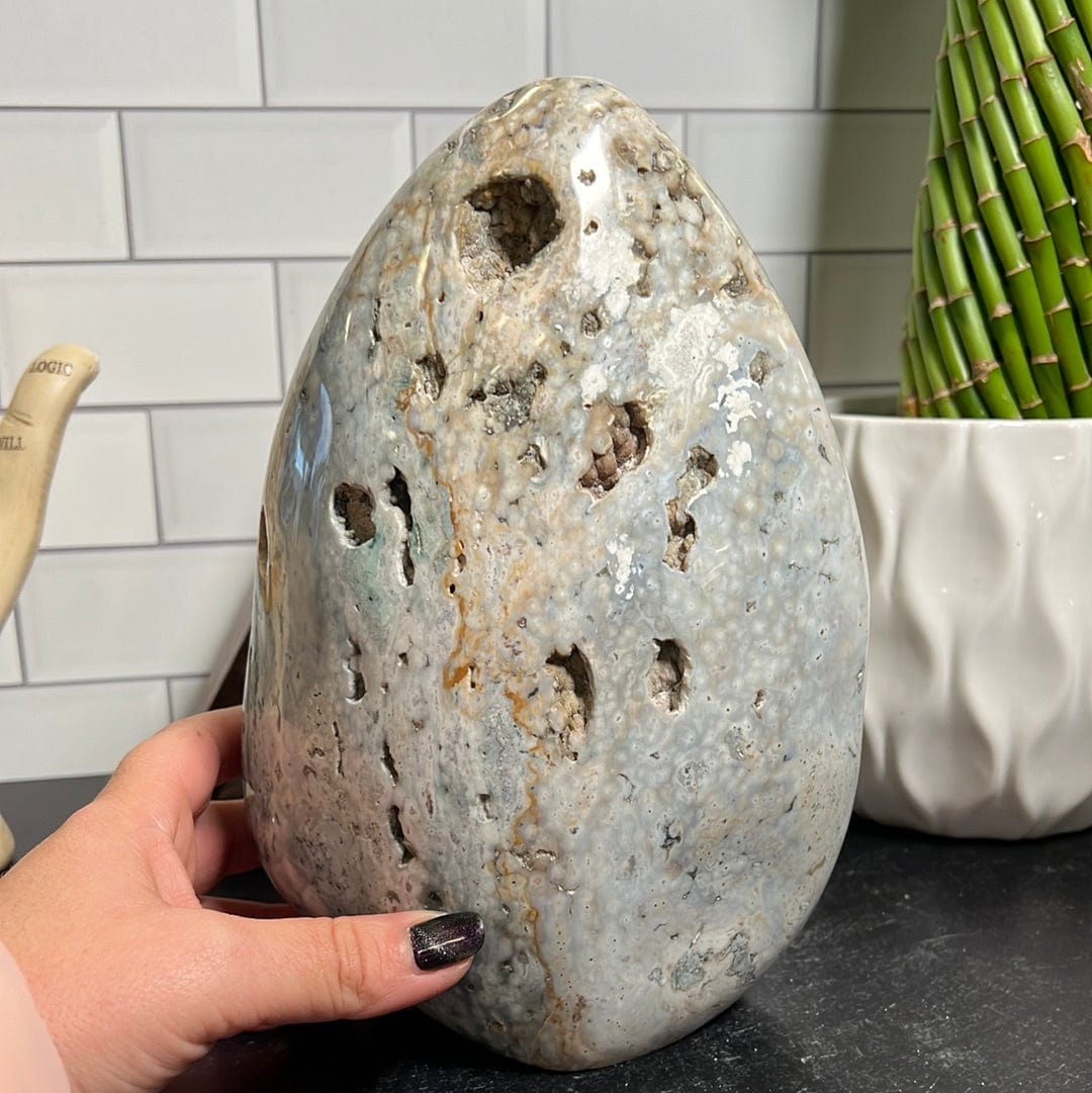 Large ocean jasper cut base.  It is mostly white with shades of green, yellow and gray.  It has a few sparkly druzy pockets along the front.