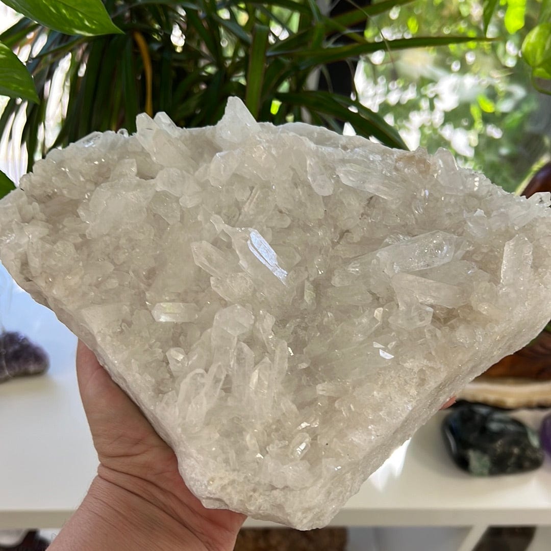 Large triangular shaped crystal cluster held in a woman's hand.