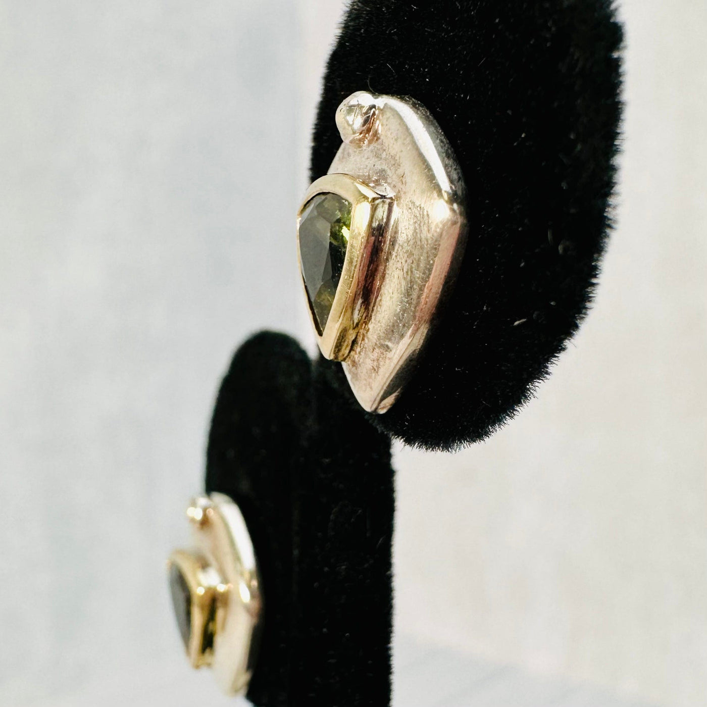 Up close side view of Moldavite earring on a black earring display.