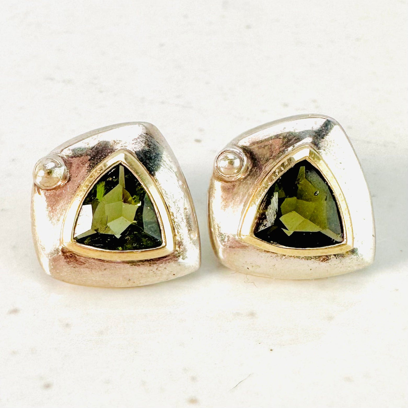 Up close view of Moldavite earrings on a white surface.