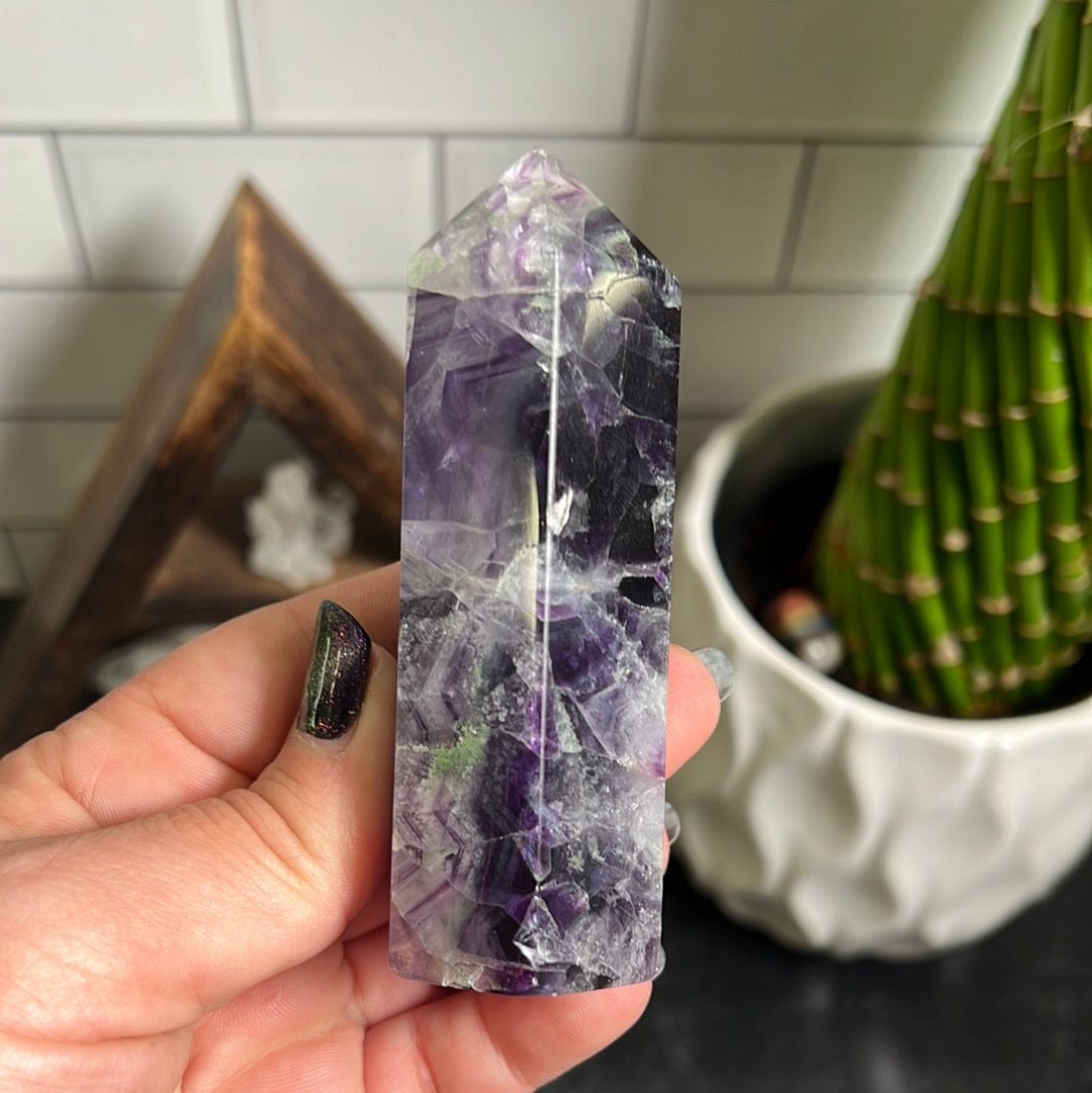 Purple polished fluorite point held in a woman's hand.