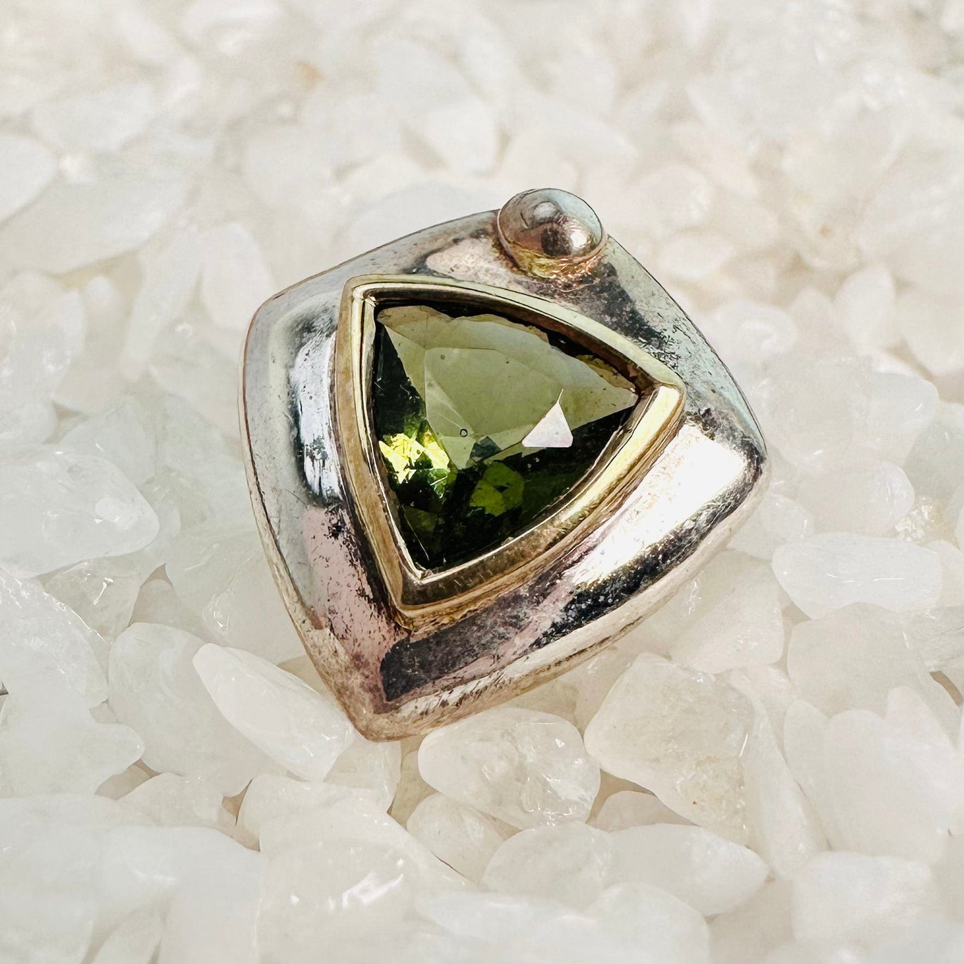Up close view of one Moldavite earring on top of crystal quartz chips.