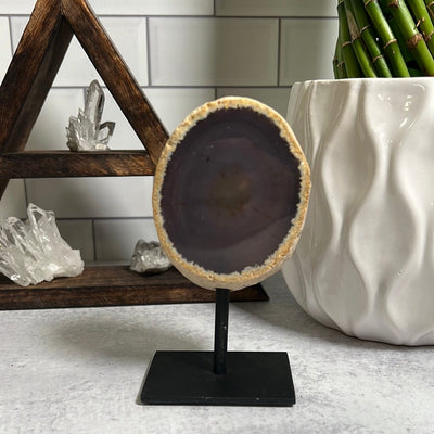 Agate geode on a black metal base.  The geode has a tan outer banding and is dark brown in the inside.