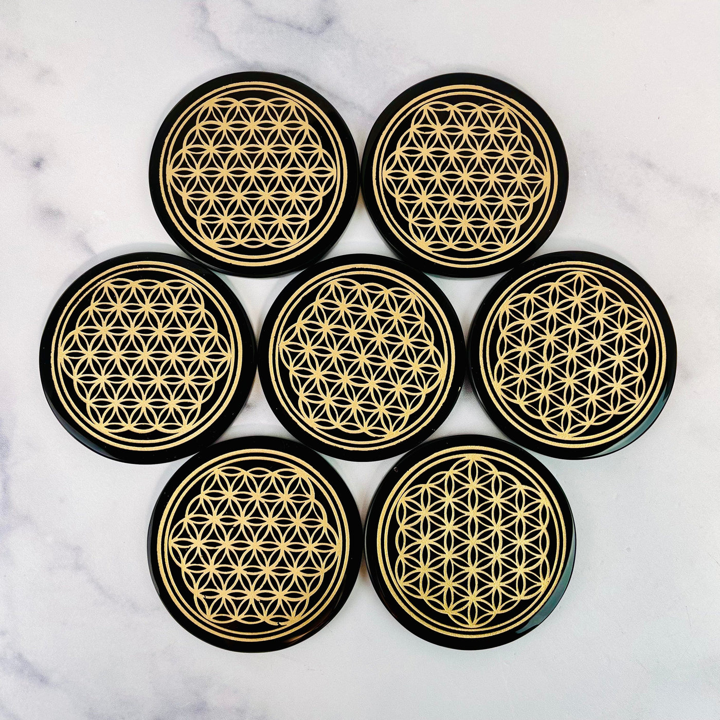 Black Obsidian Coasters laid out on a marble surface in a flower shape.