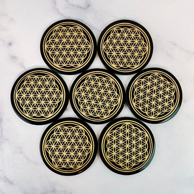 Black Obsidian Coasters laid out on a marble surface in a flower shape.