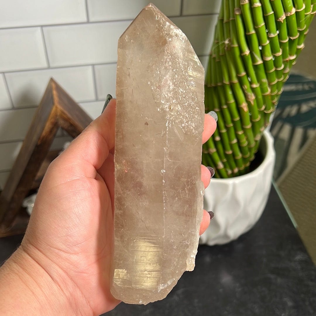 Natural smokey quartz point in a woman's hand.