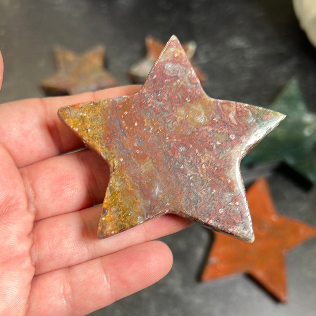 Red and yellow jasper star in a woman's hand.