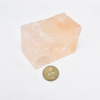 Pink Calcite Oblique Rectangular Prism pictured alongside a quarter for size reference